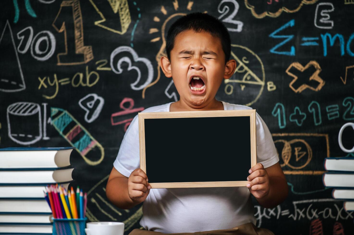 niño sentado y sosteniendo la pizarra en el aula foto