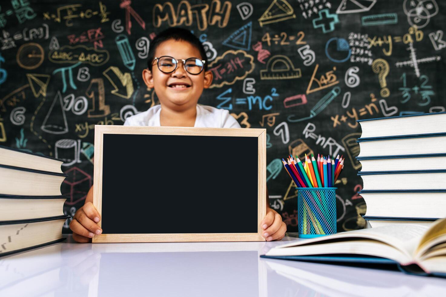 niño sentado y sosteniendo la pizarra en el aula foto