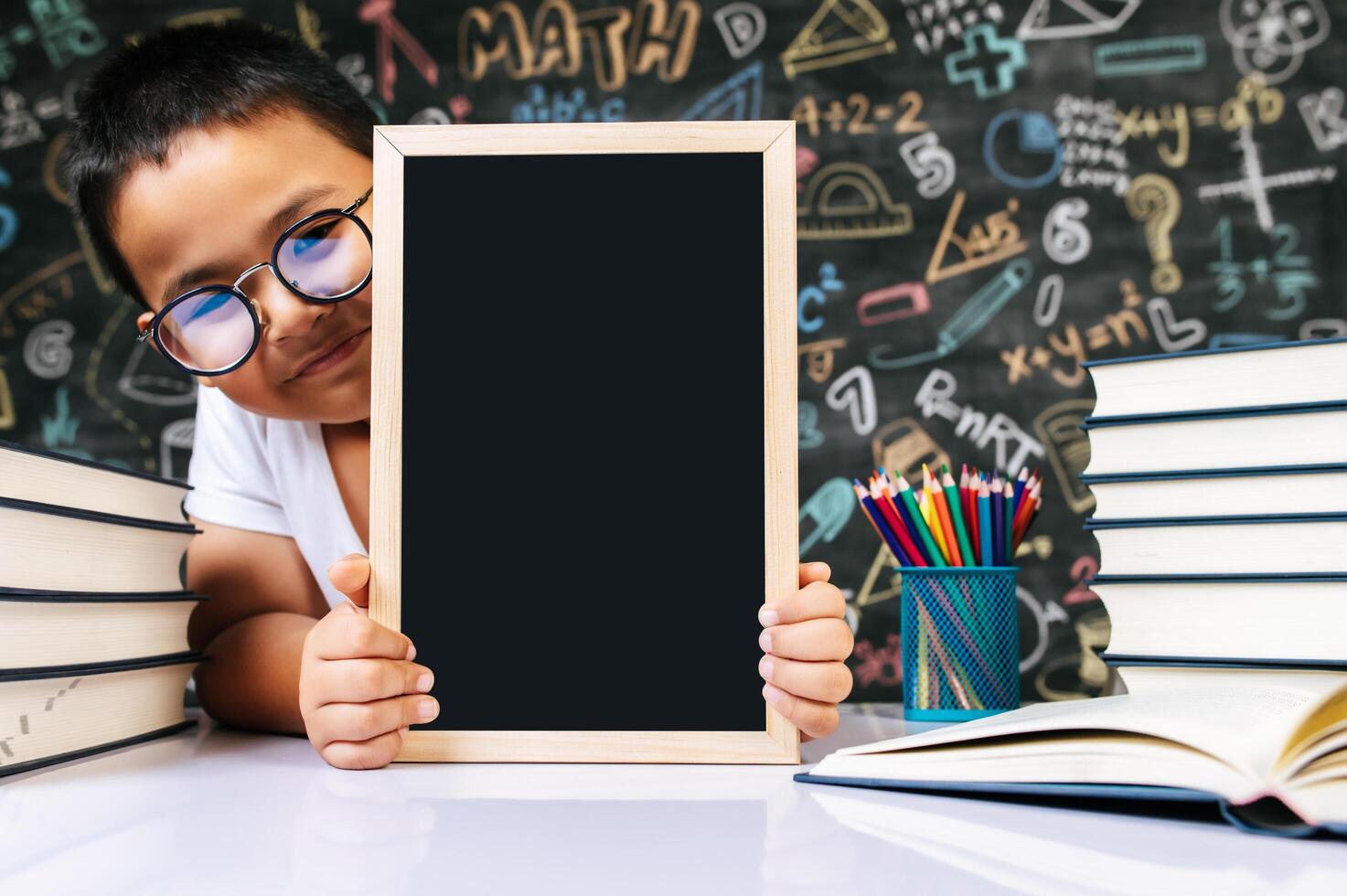 niño sentado y sosteniendo la pizarra en el aula foto