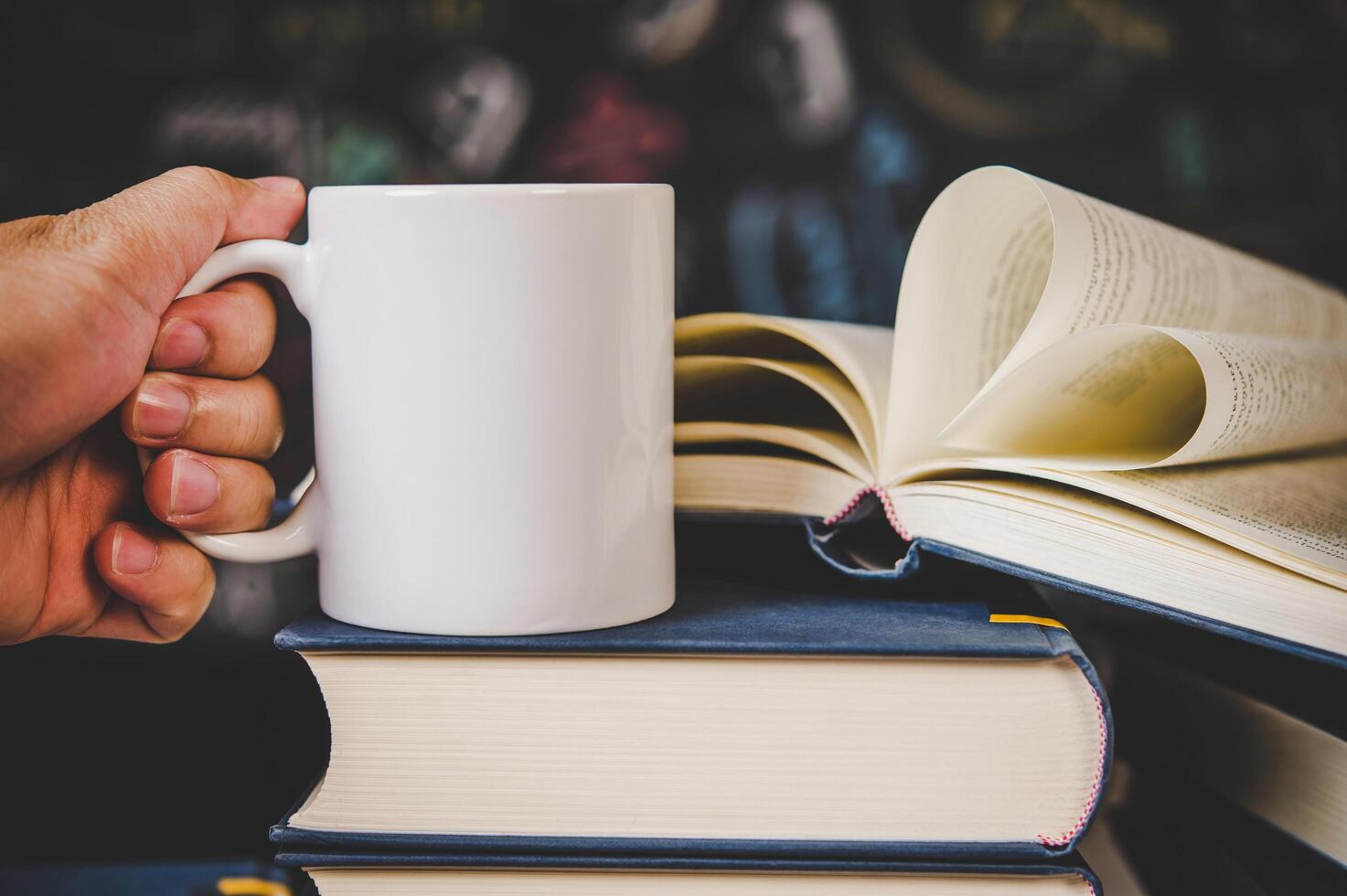 The hand was picking up the cup on top of the book in the classroom. photo