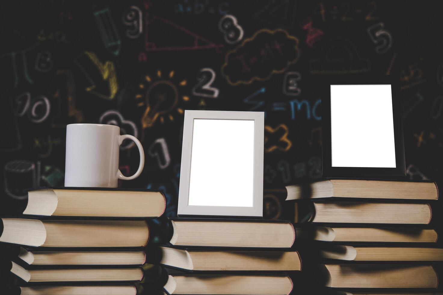 cup, black photo frame and white photo frame on books in classroom