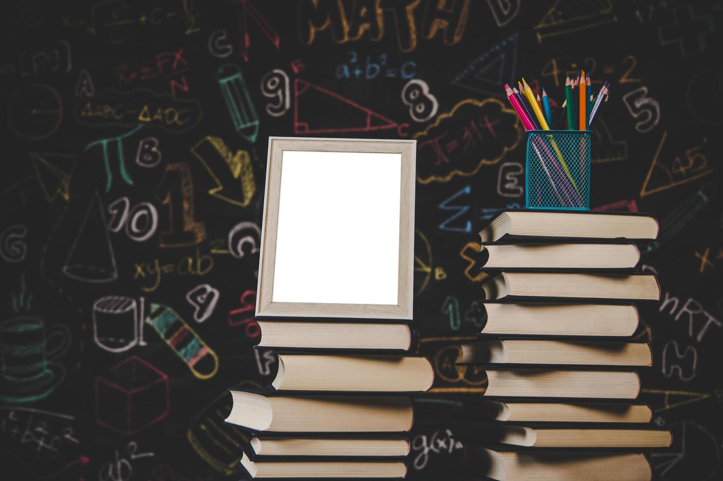 white photo frame and colored pencils on books in classroom