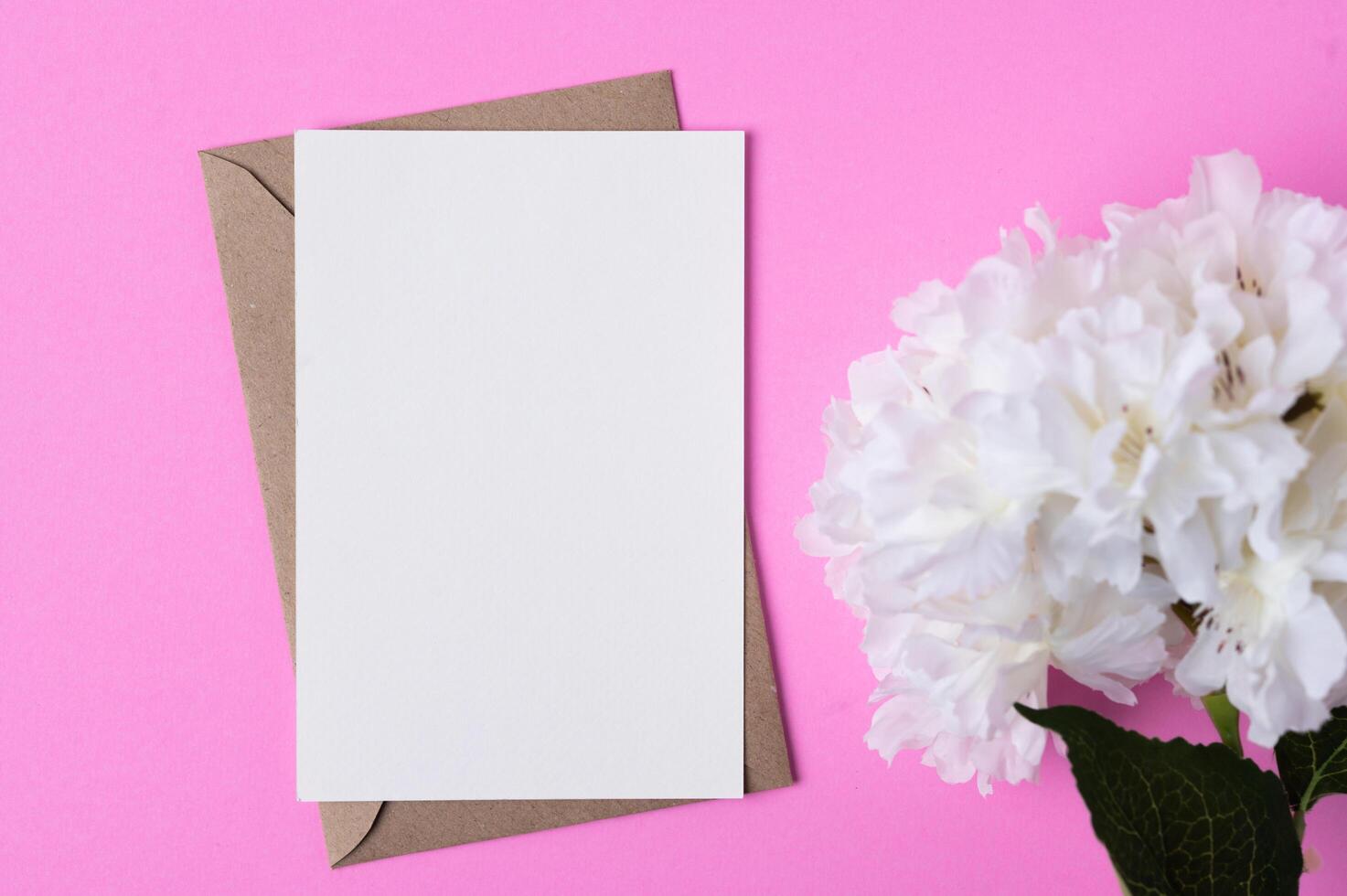 Blank paper with flowers placed on a pink background photo