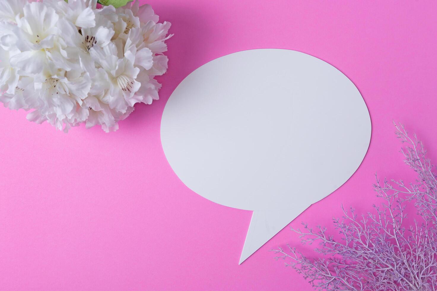 Speech symbols made of paper and flowers placed on a pink background. photo