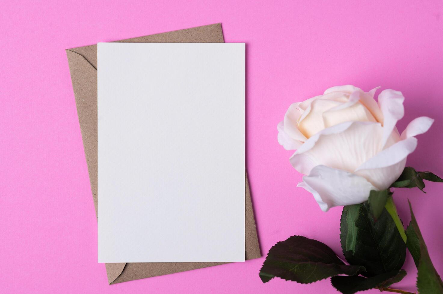 Blank paper with flowers placed on a pink background photo