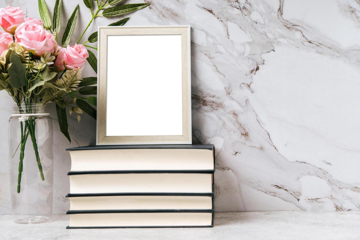 A picture frame placed on a book with a flower vase photo