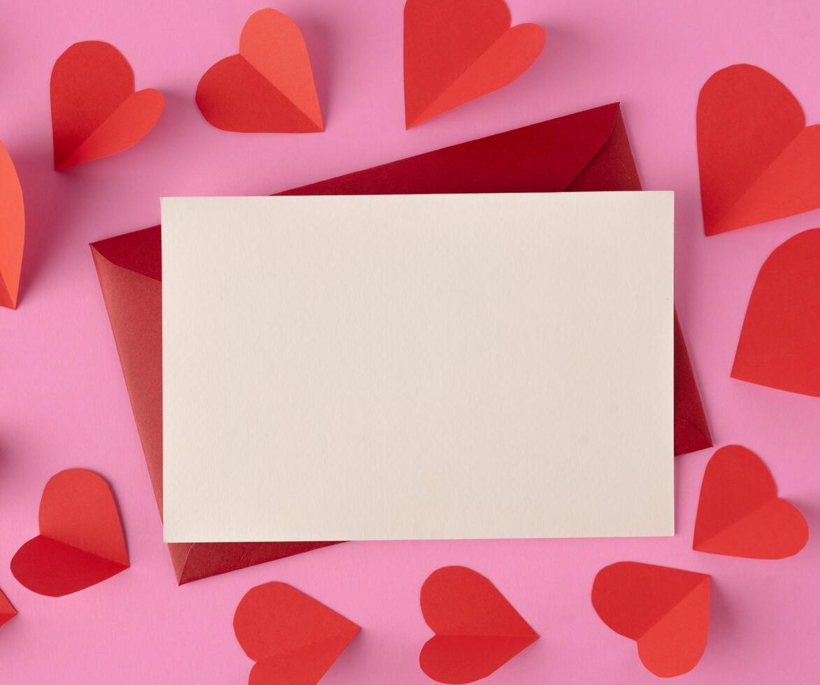 White paper and red hearts are placed on a pink background. photo