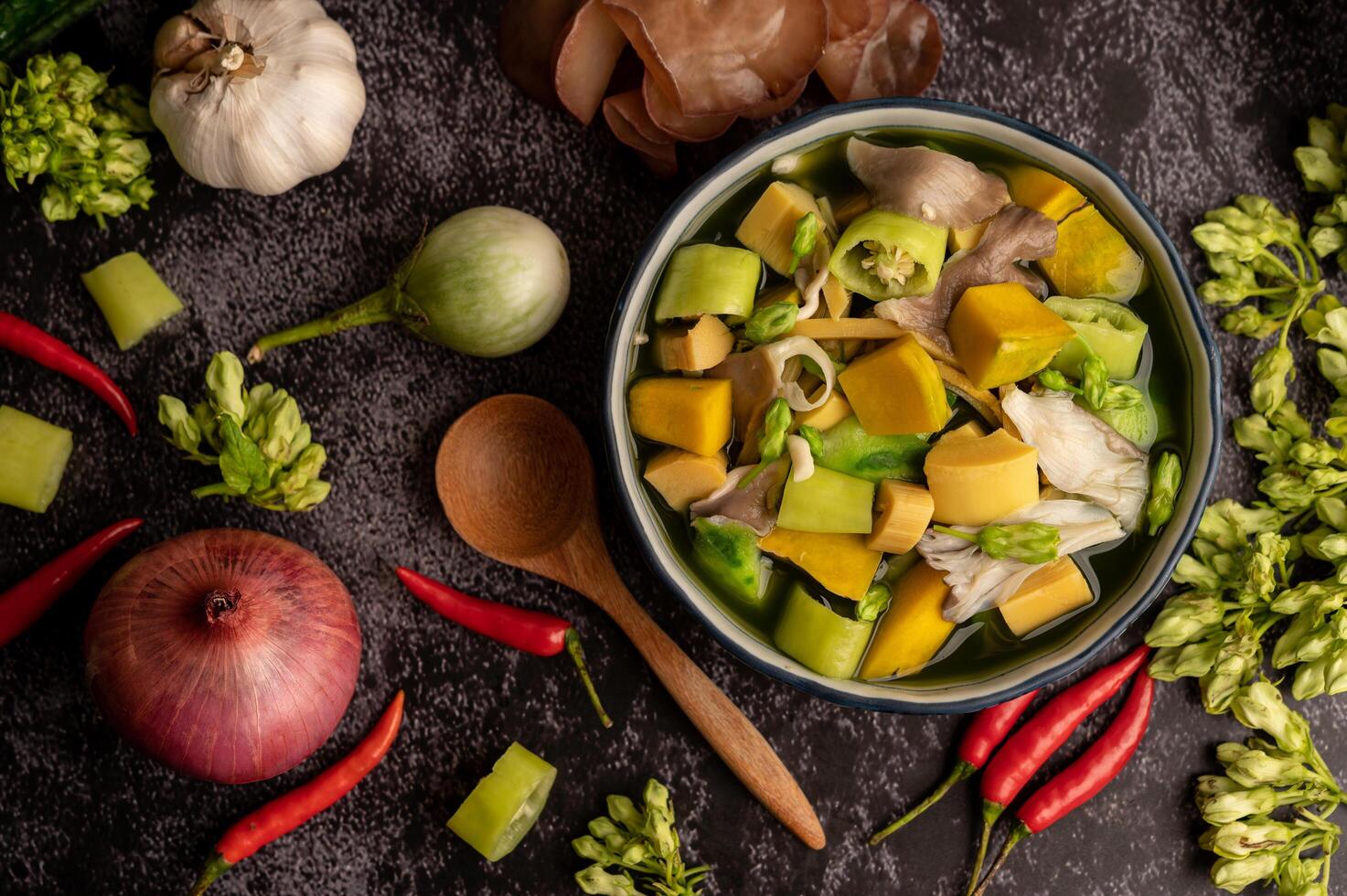 Kaeng Liang in a bowl with spices on a black cement floor. photo