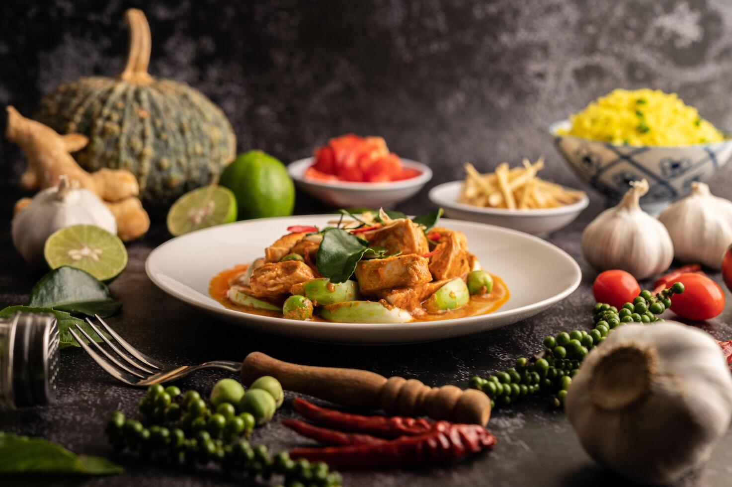 Dry green curry with chicken in white plates on black cement photo