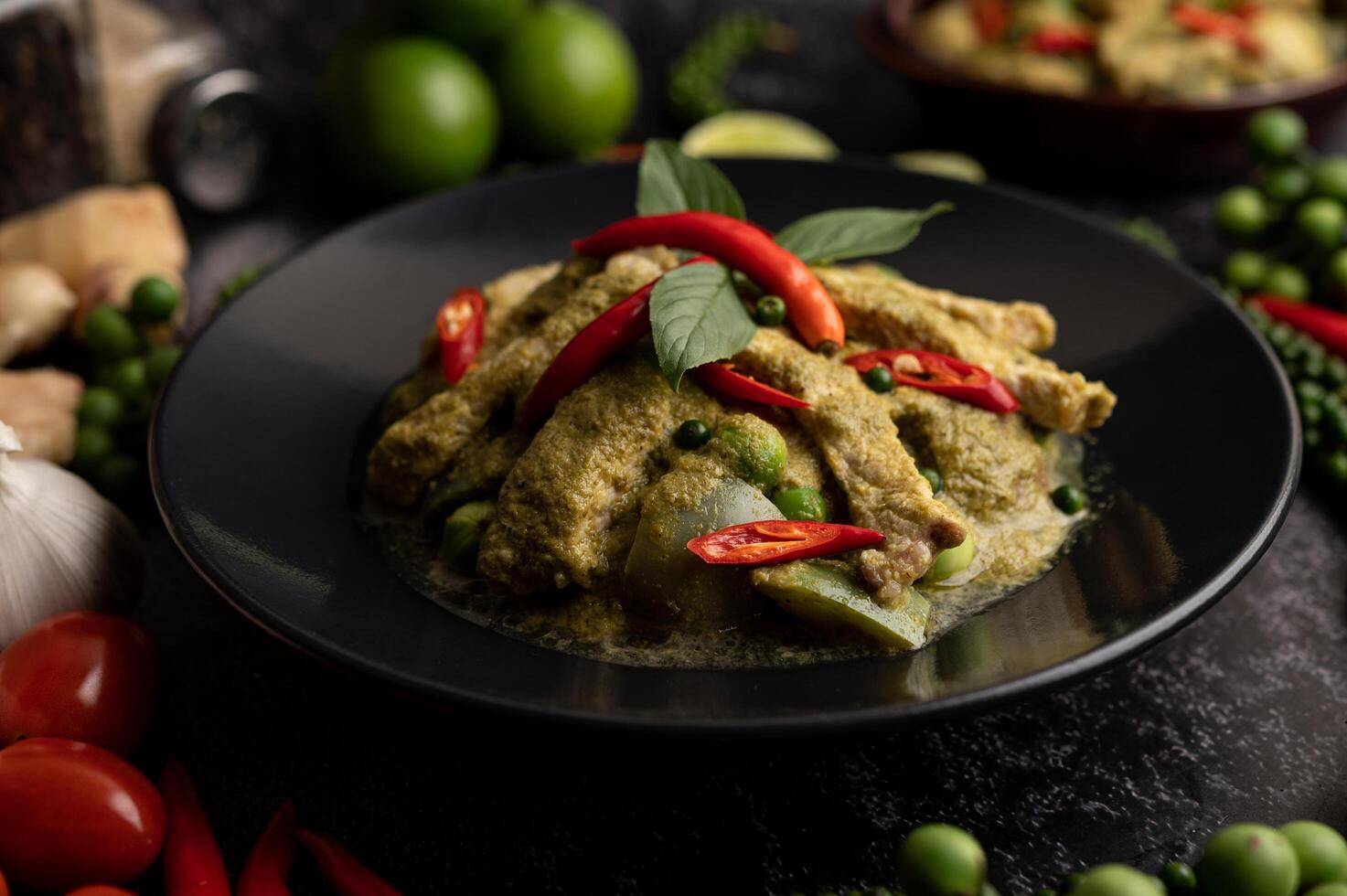 Pork green curry in black plate with spices on black cement background photo