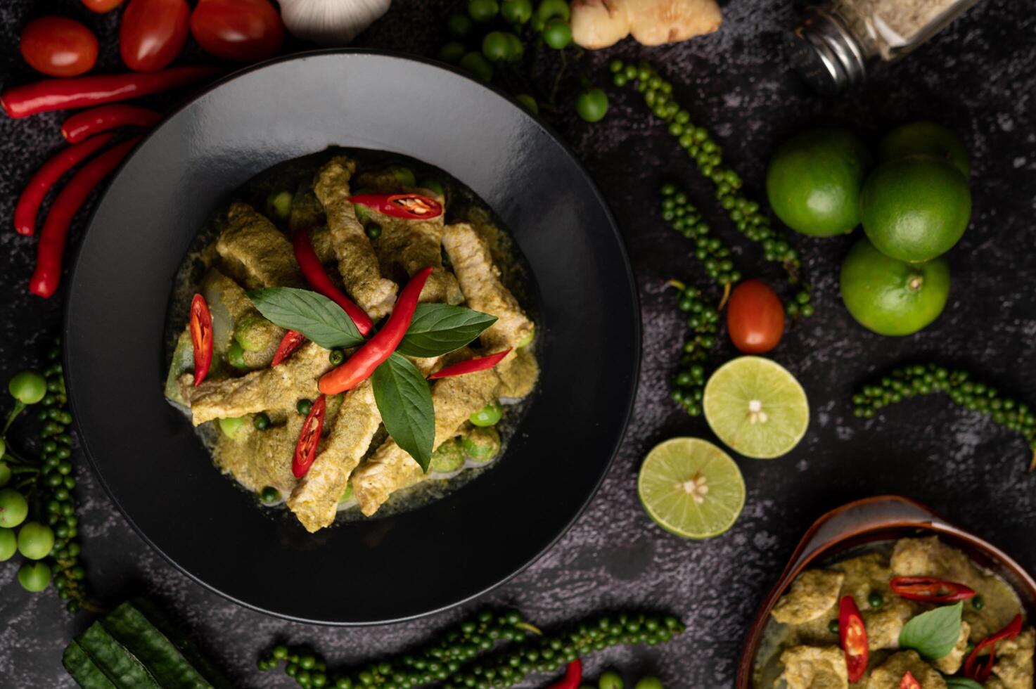 Pork green curry in black plate with spices on black cement background photo