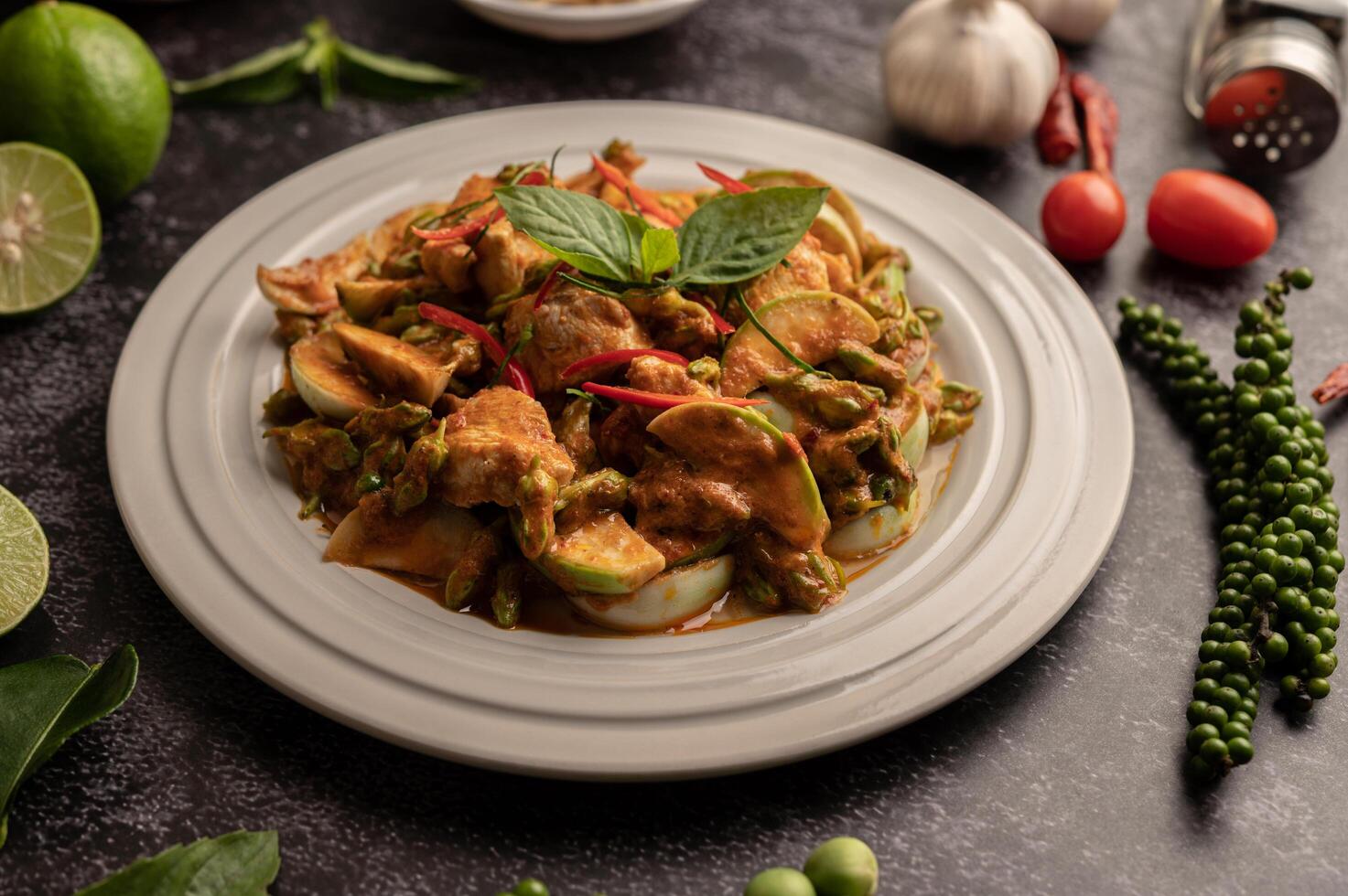 Dry green curry with chicken in white plates on black cement photo