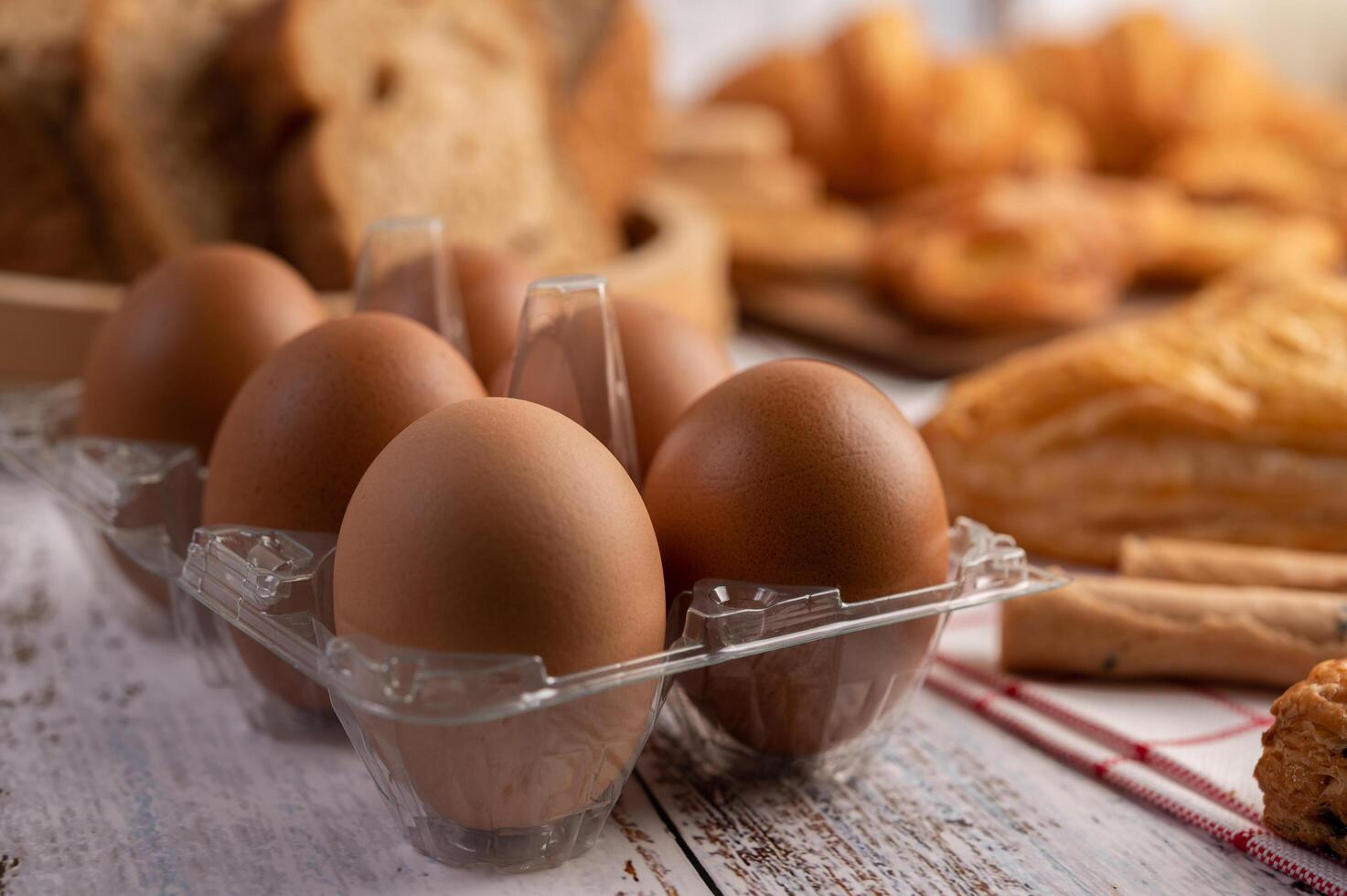 huevos en paneles de plástico y pan que se coloca sobre una mesa de madera blanca foto