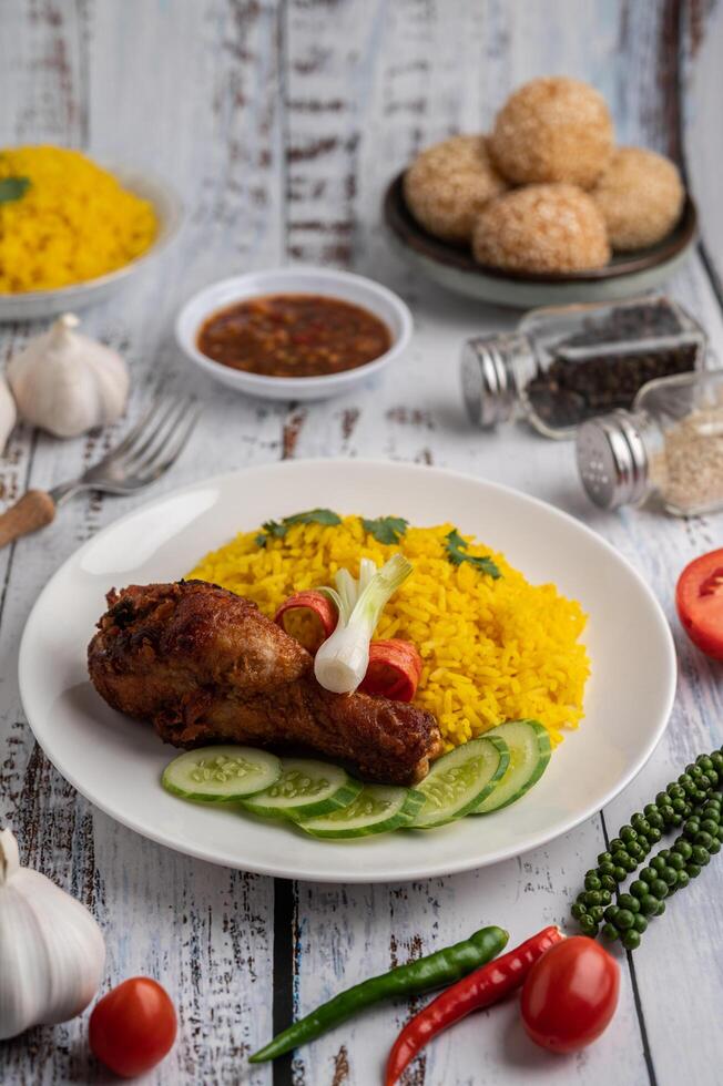 Biryani de pollo en un plato con especias sobre un piso de madera blanca foto