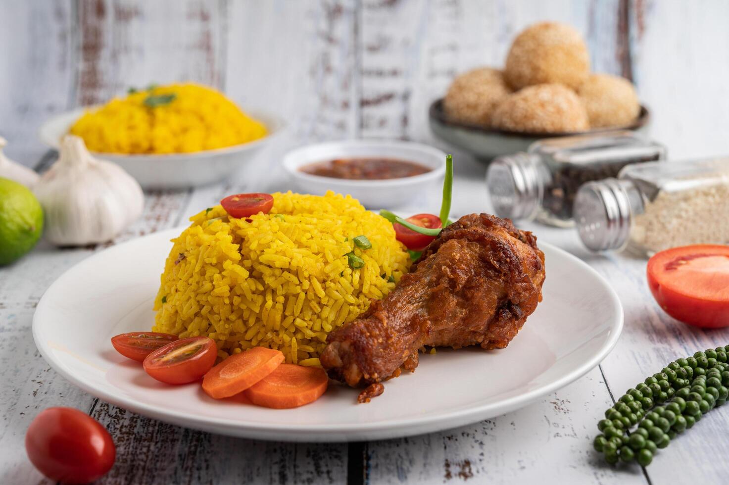 Biryani de pollo en un plato con especias sobre un piso de madera blanca foto