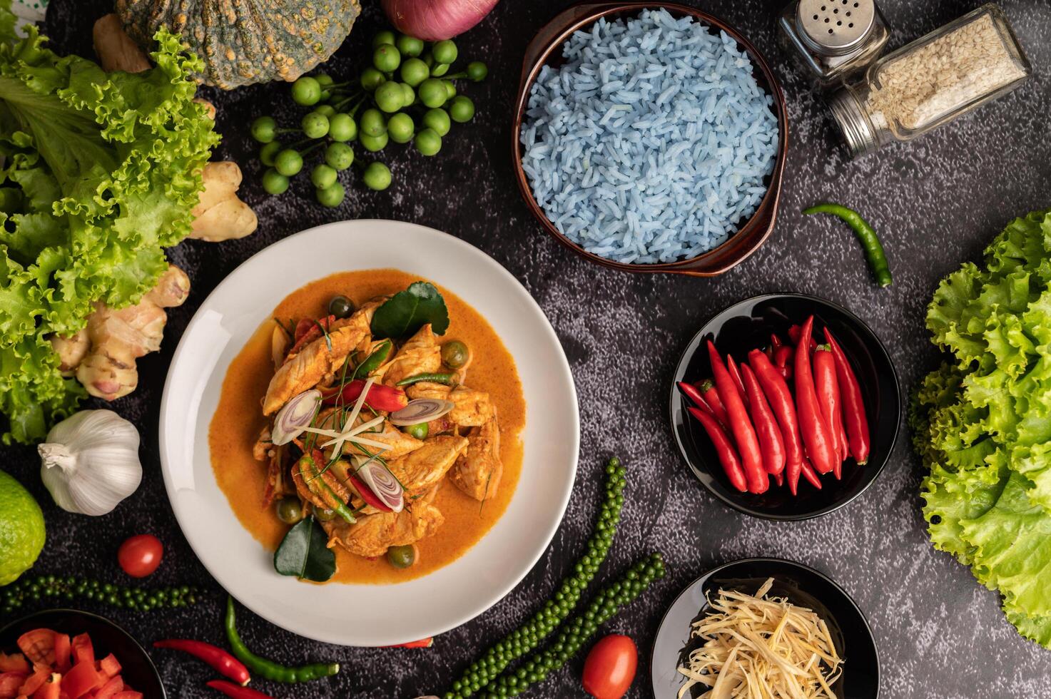 Dry green curry with chicken in white plates on black cement photo