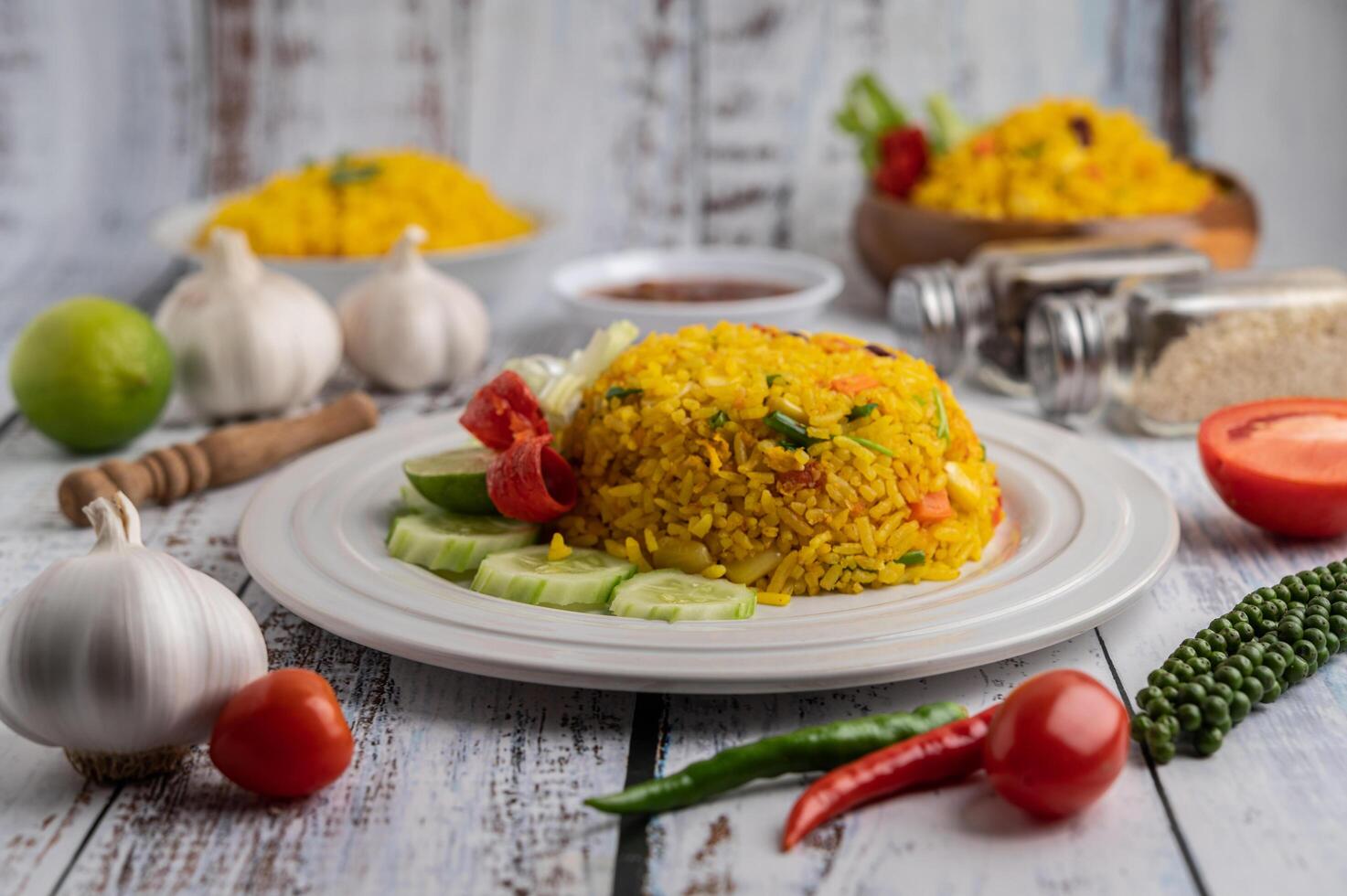 Arroz con cúrcuma en un plato blanco con especias sobre un piso de madera blanca foto