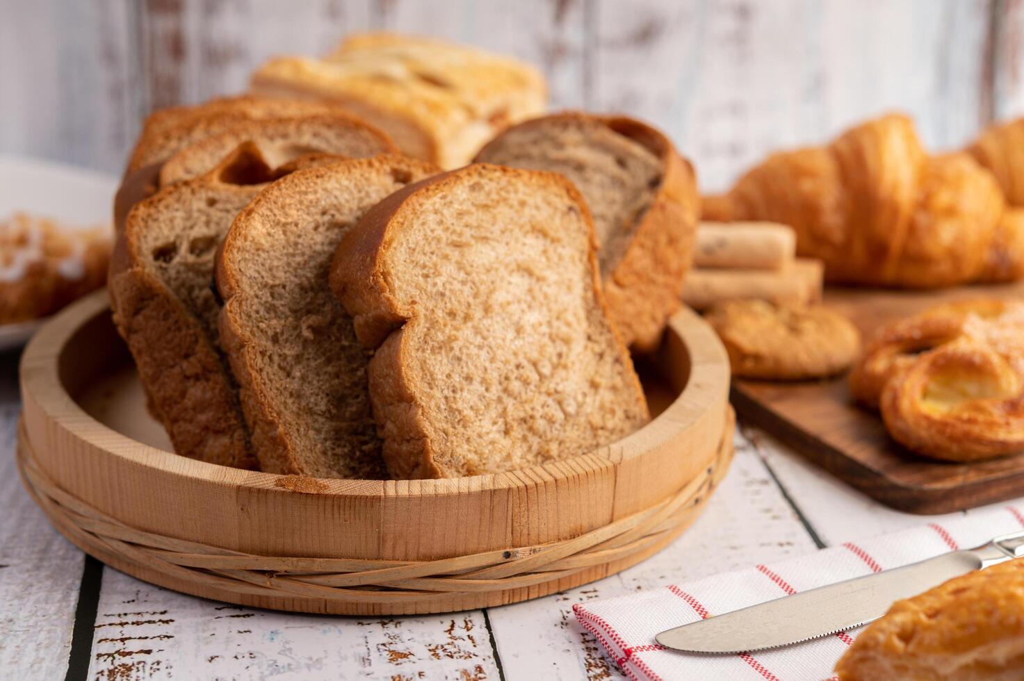 Bread slices placed in a wooden plate on a white wooden table. photo