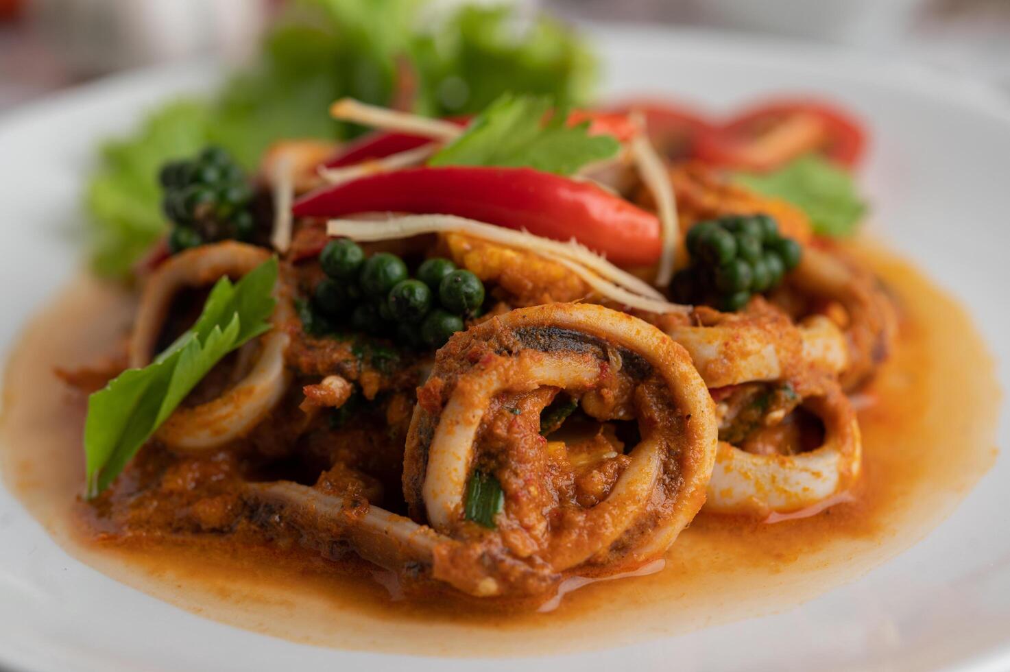 Calamares salteados con pasta de curry en plato blanco. foto