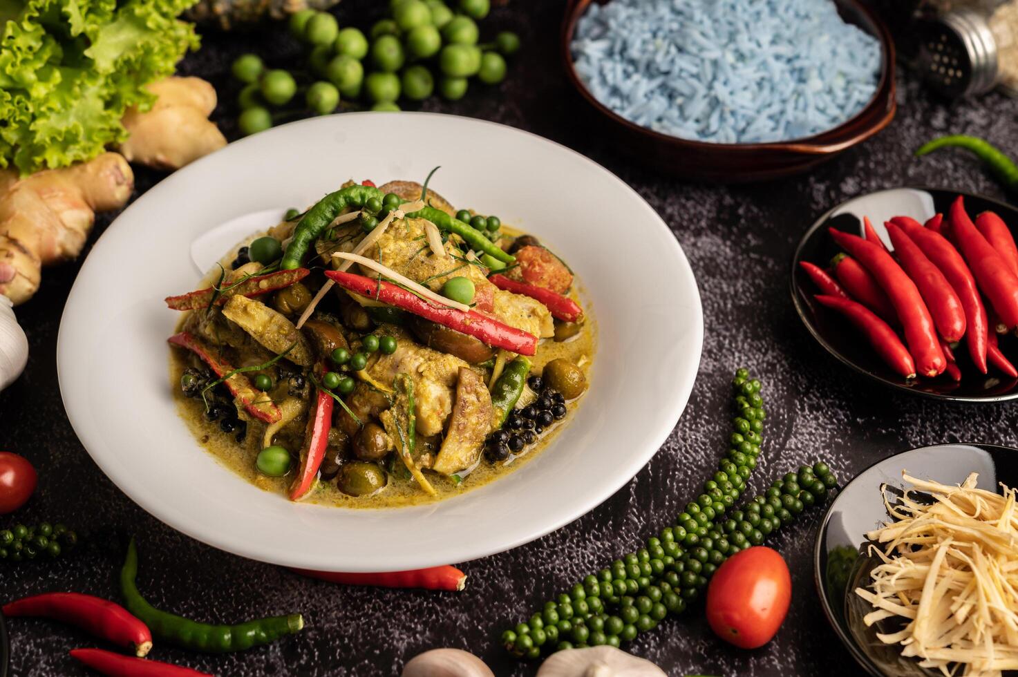 Stir Fried Spicy Chicken in white plate with spices on black cement. photo