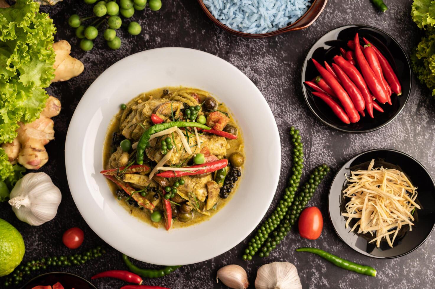 Stir Fried Spicy Chicken in white plate with spices on black cement. photo