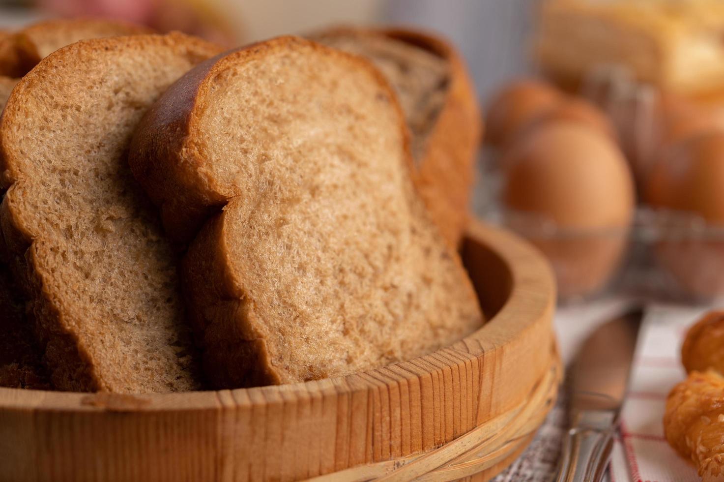 rebanadas de pan colocadas en un plato de madera sobre una mesa de madera blanca. foto