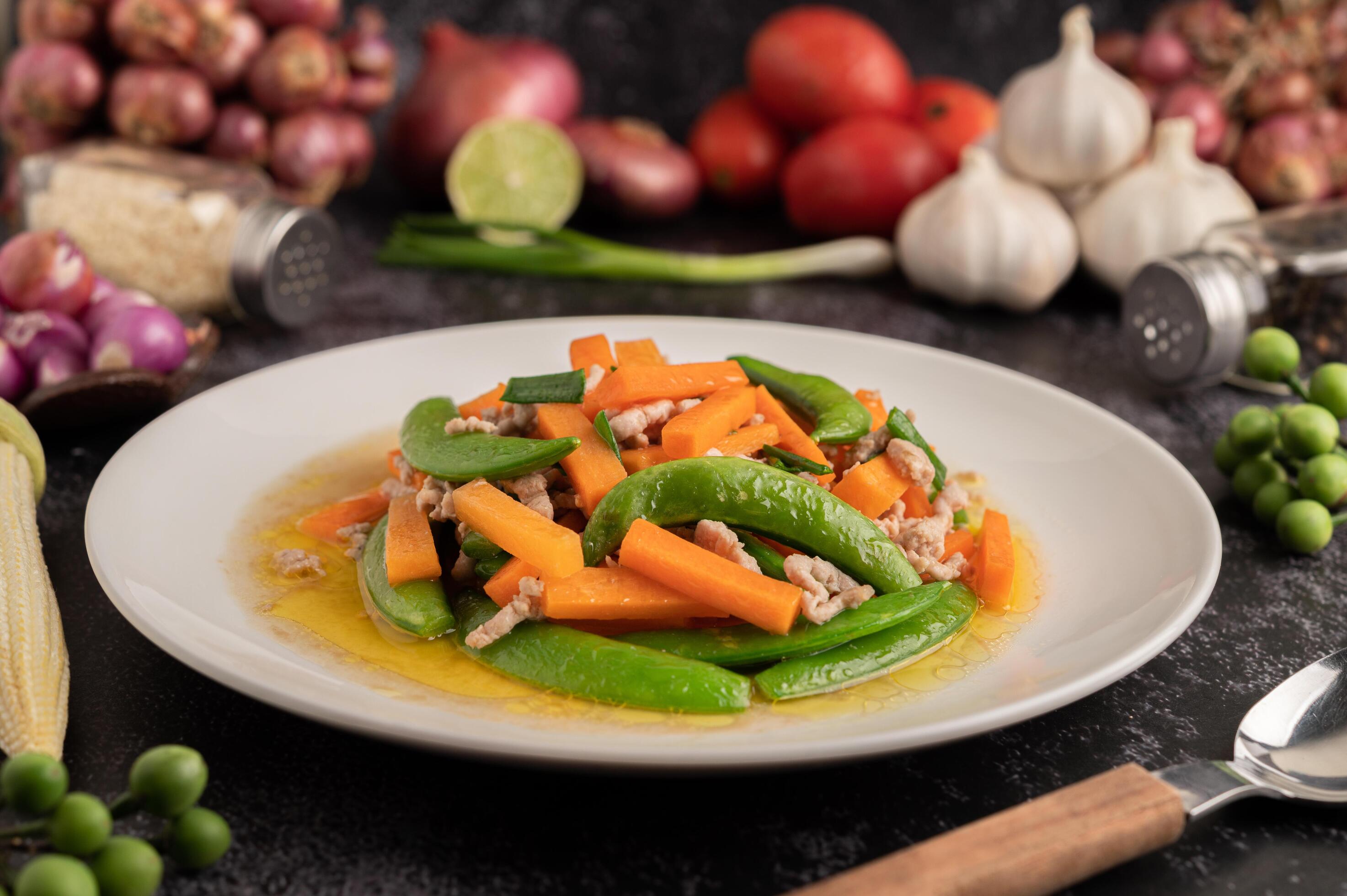 Stir fried green peas and minced pork carrots on a white plate. 3384558