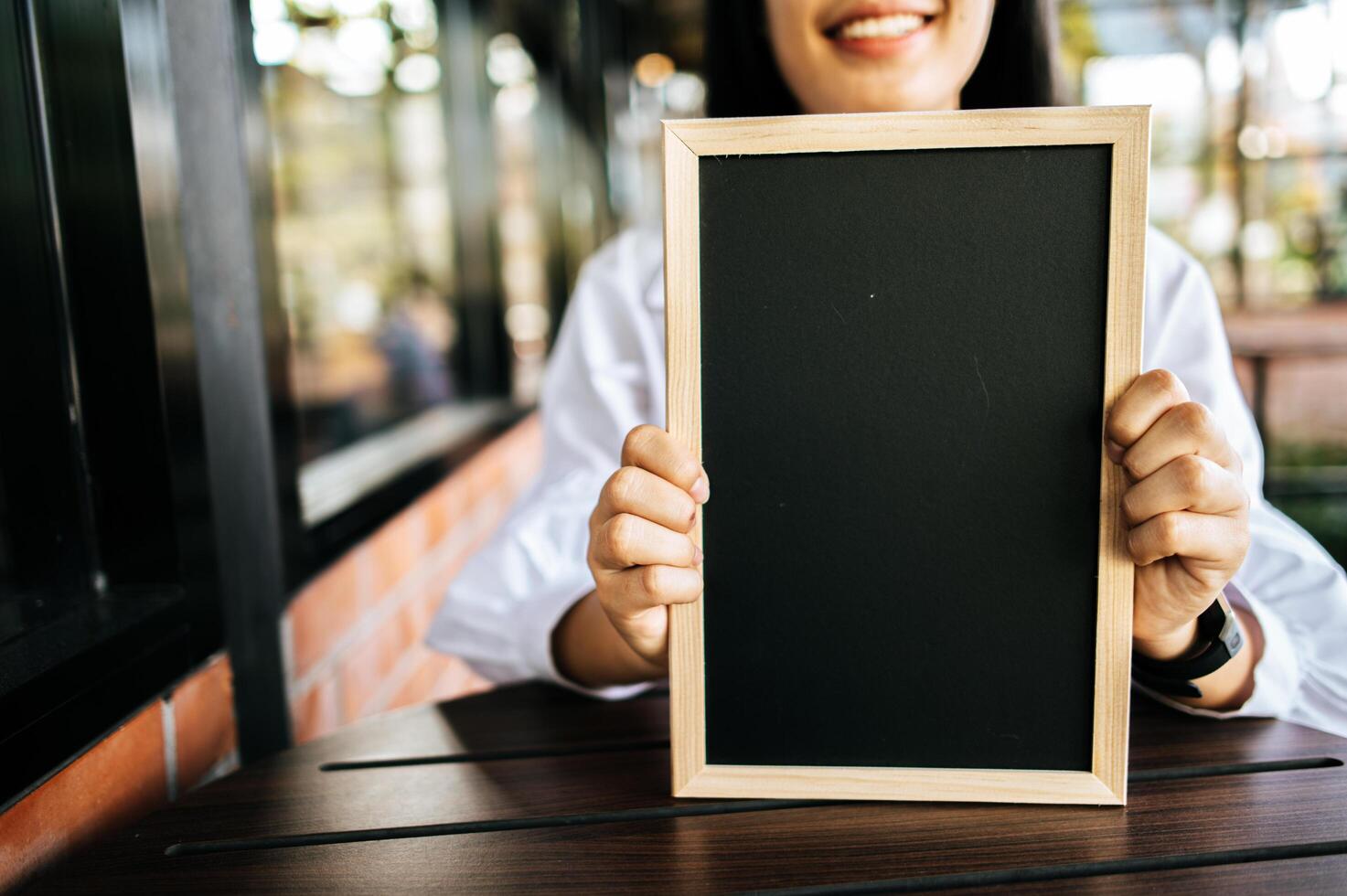 smile woman holding black board in cafe photo