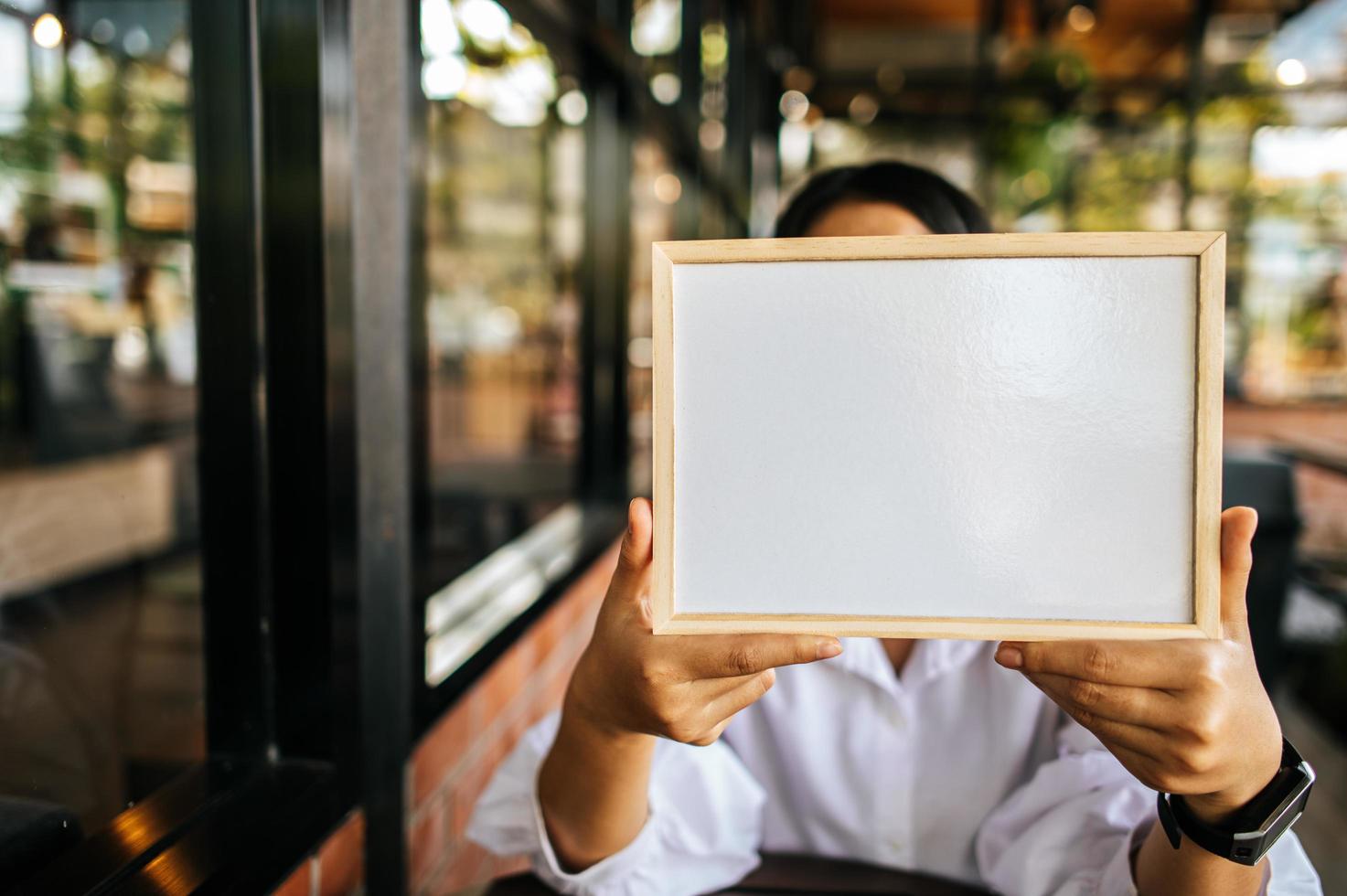 woman holding white board in cafe photo