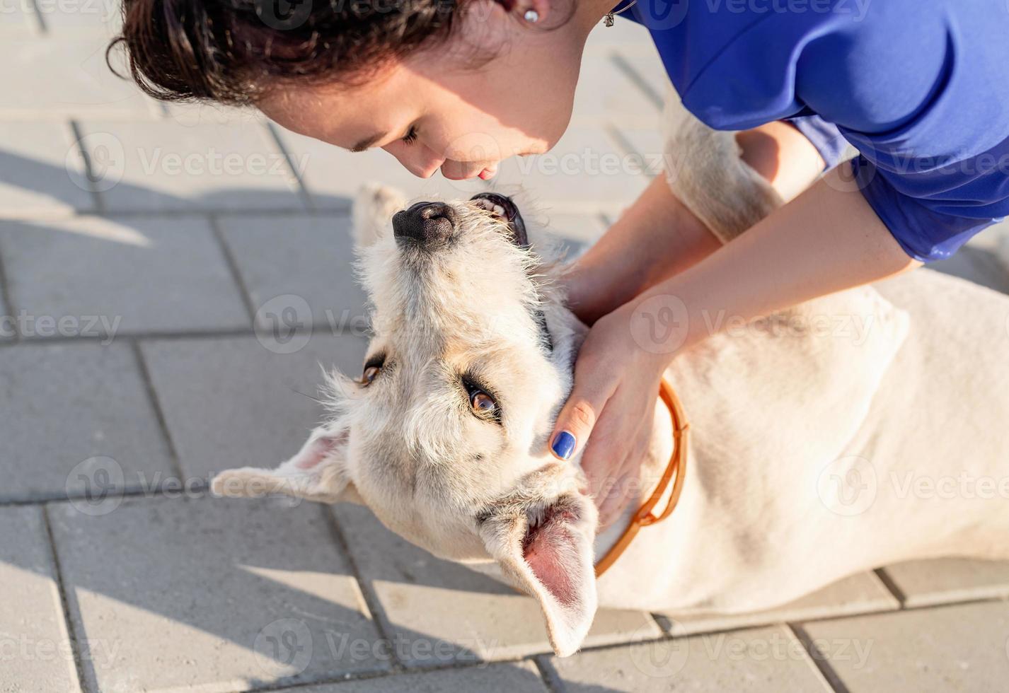 Atractiva mujer joven besando a su perro en la calle foto