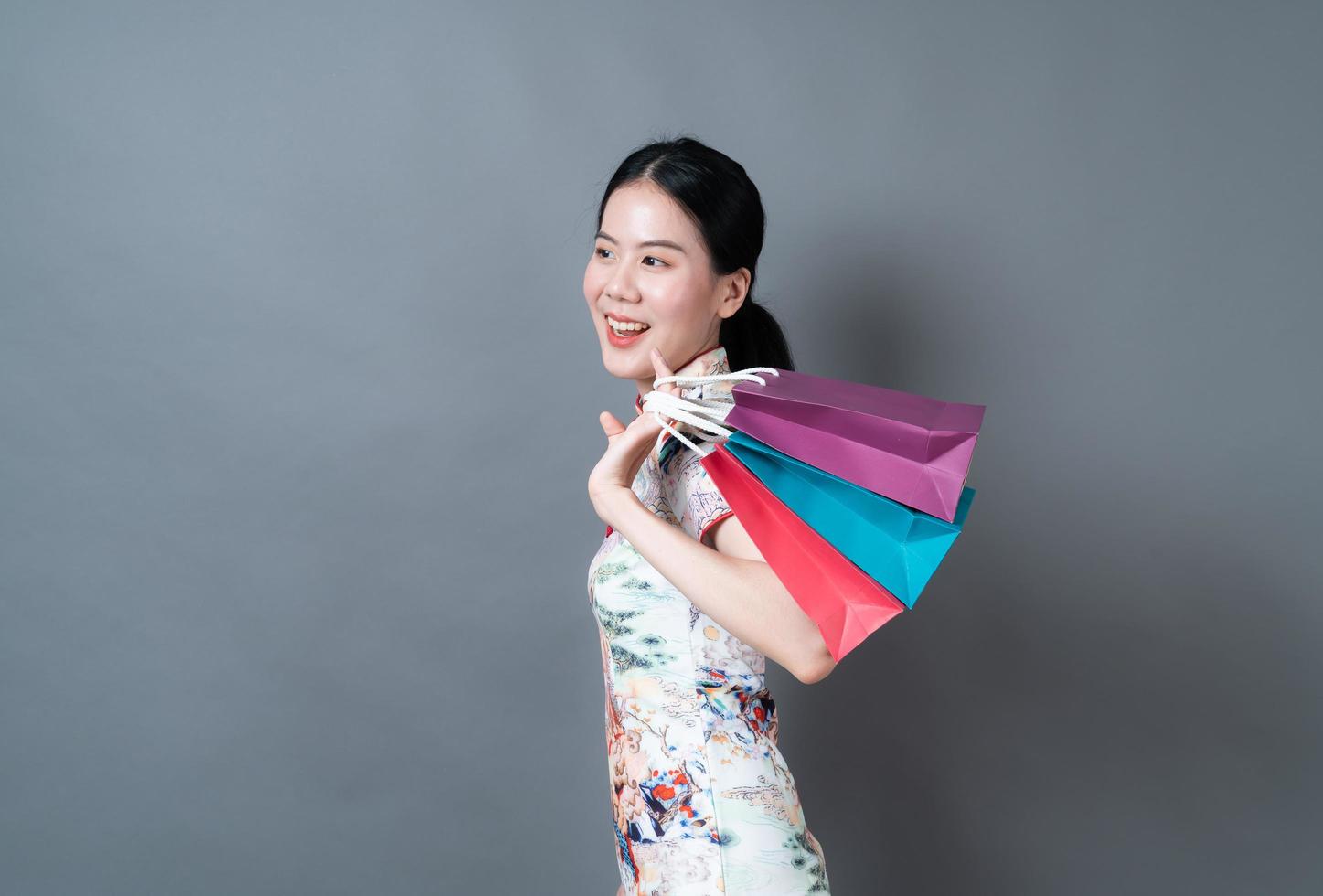 mujer asiática vistiendo traje tradicional chino y sosteniendo una bolsa de compras foto