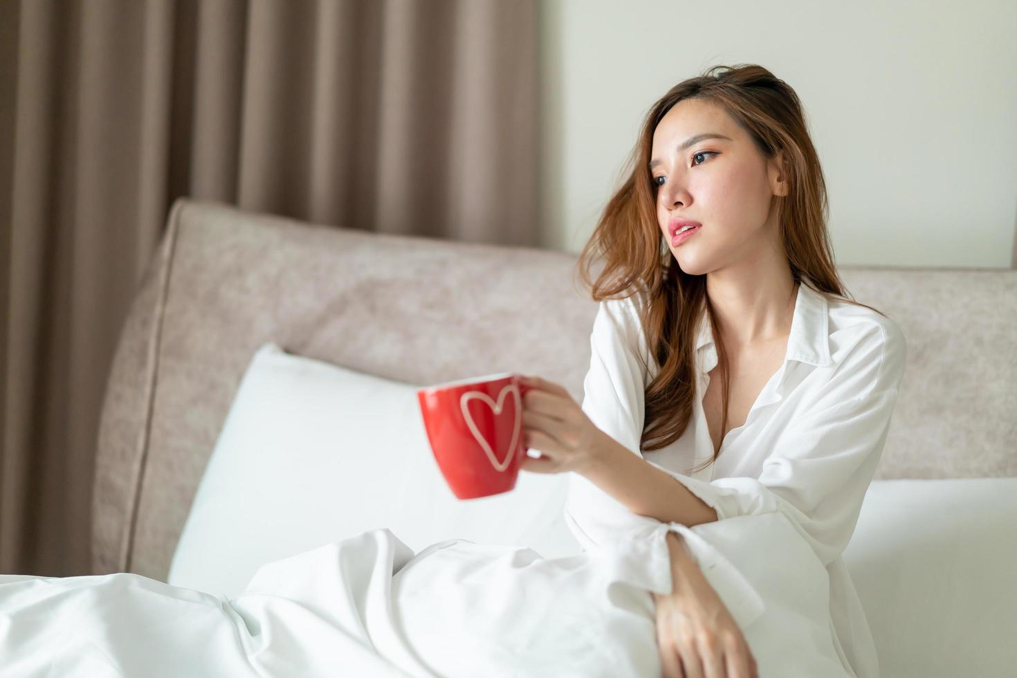 retrato, mujer hermosa, despertar, y, tenencia, taza de café, o, taza, en cama foto