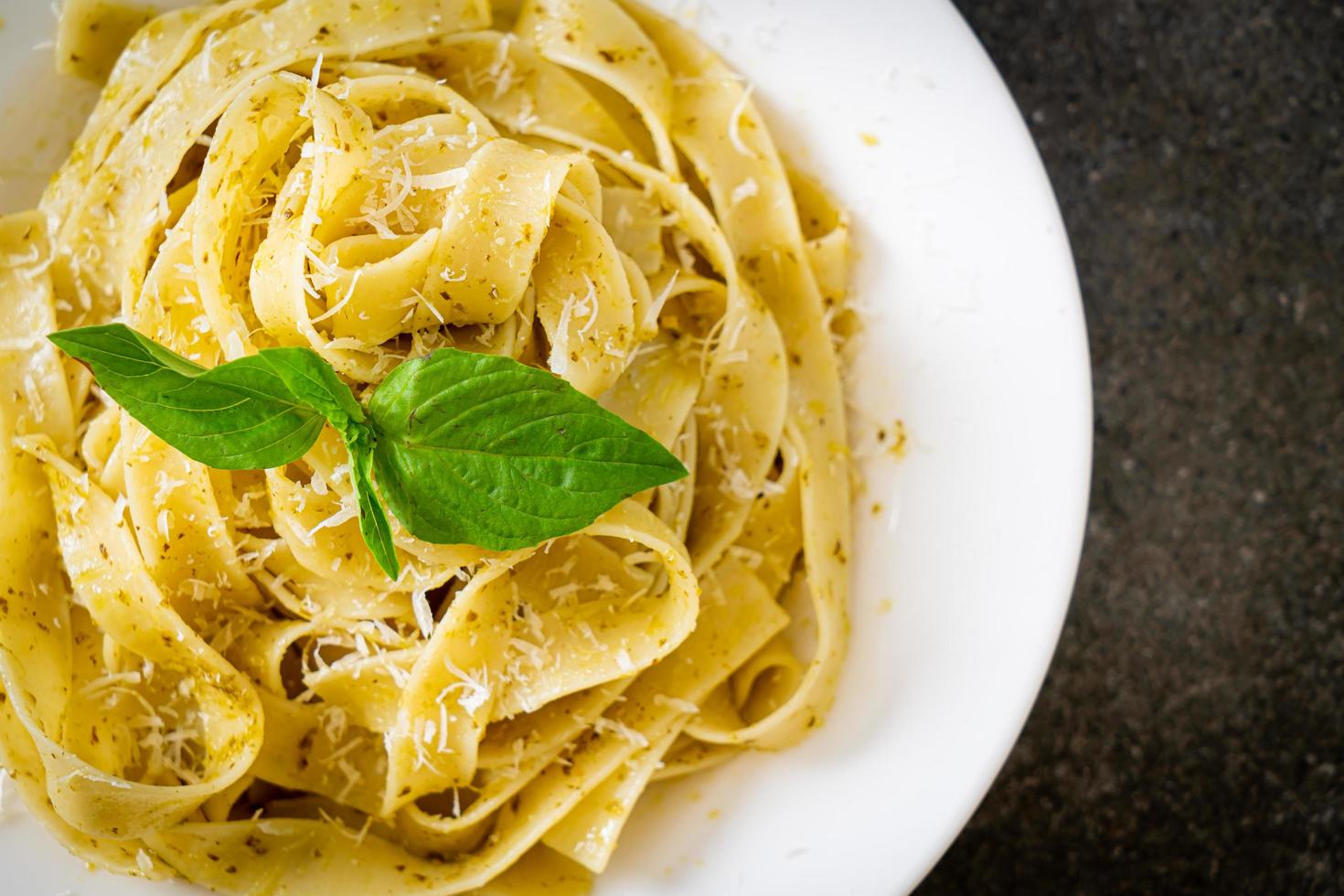 pasta fettuccine al pesto con queso parmesano encima foto