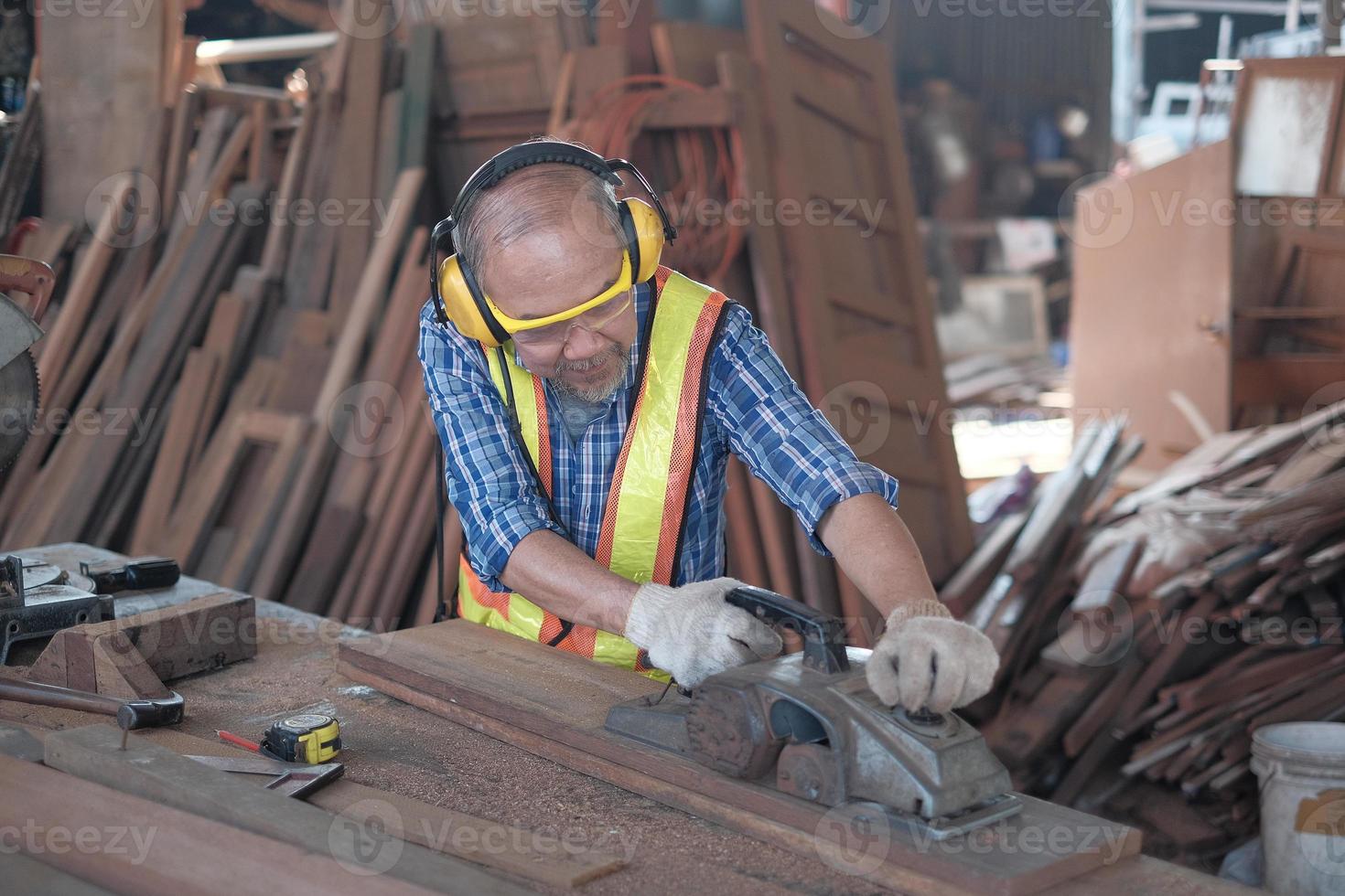 Senior male carpenter is working in wooden sawmill factory. photo