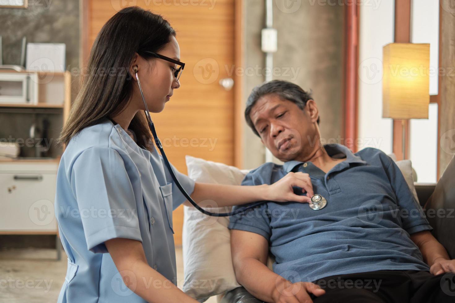 Doctora comprobando la salud del paciente masculino anciano asiático en casa. foto