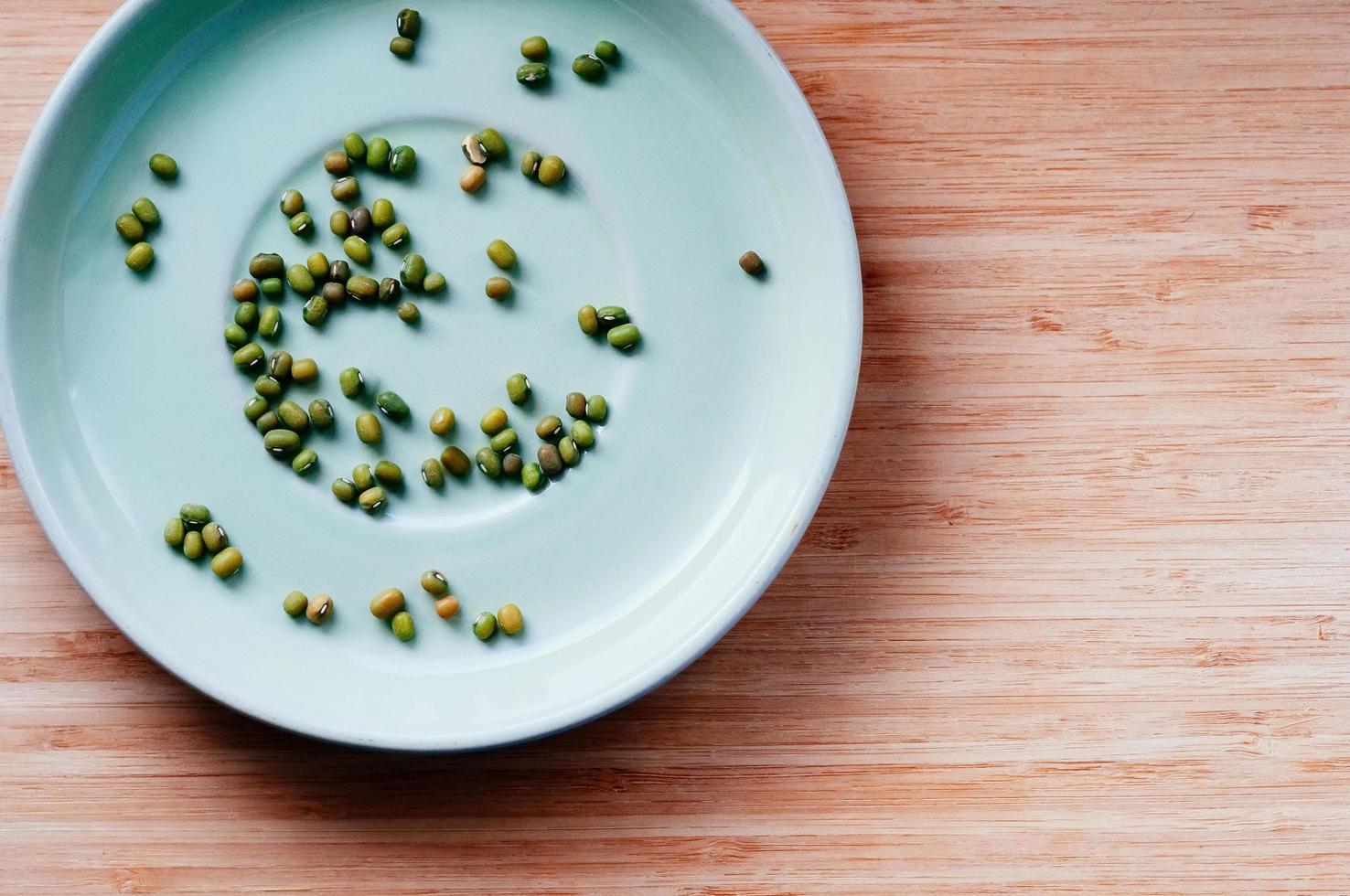 green dry mung beans scattered on saucer, top view photo