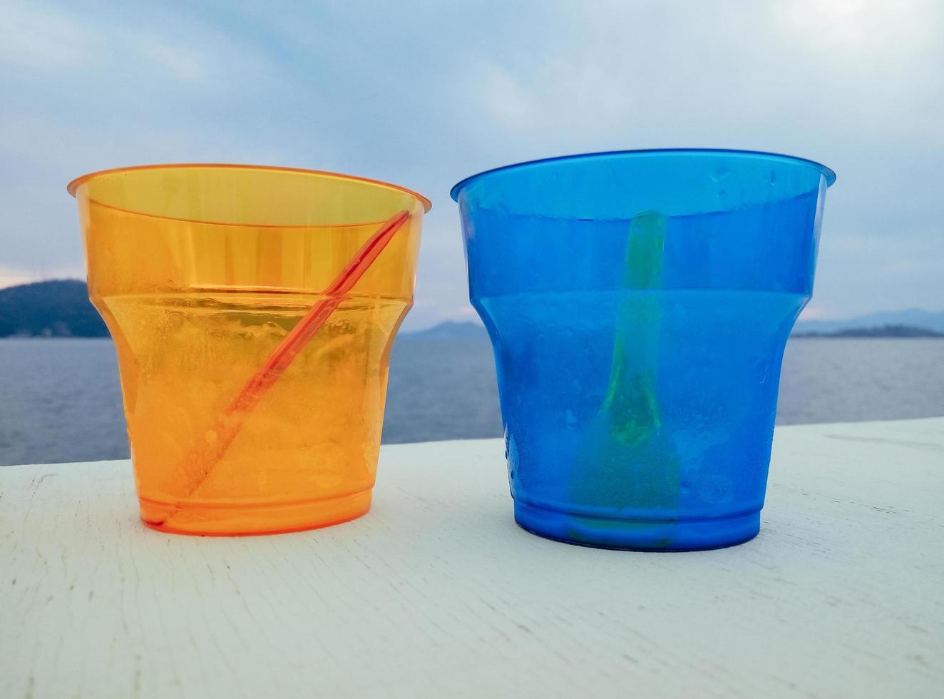 Dos coloridos vasos de plástico vacíos en la playa foto