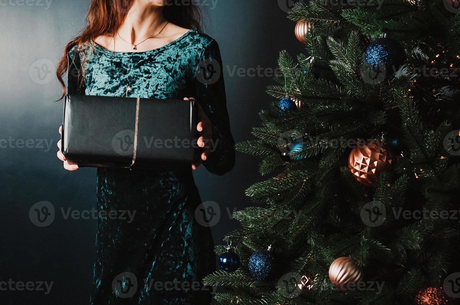 hermosa mujer con caja de regalo cerca del árbol de navidad foto