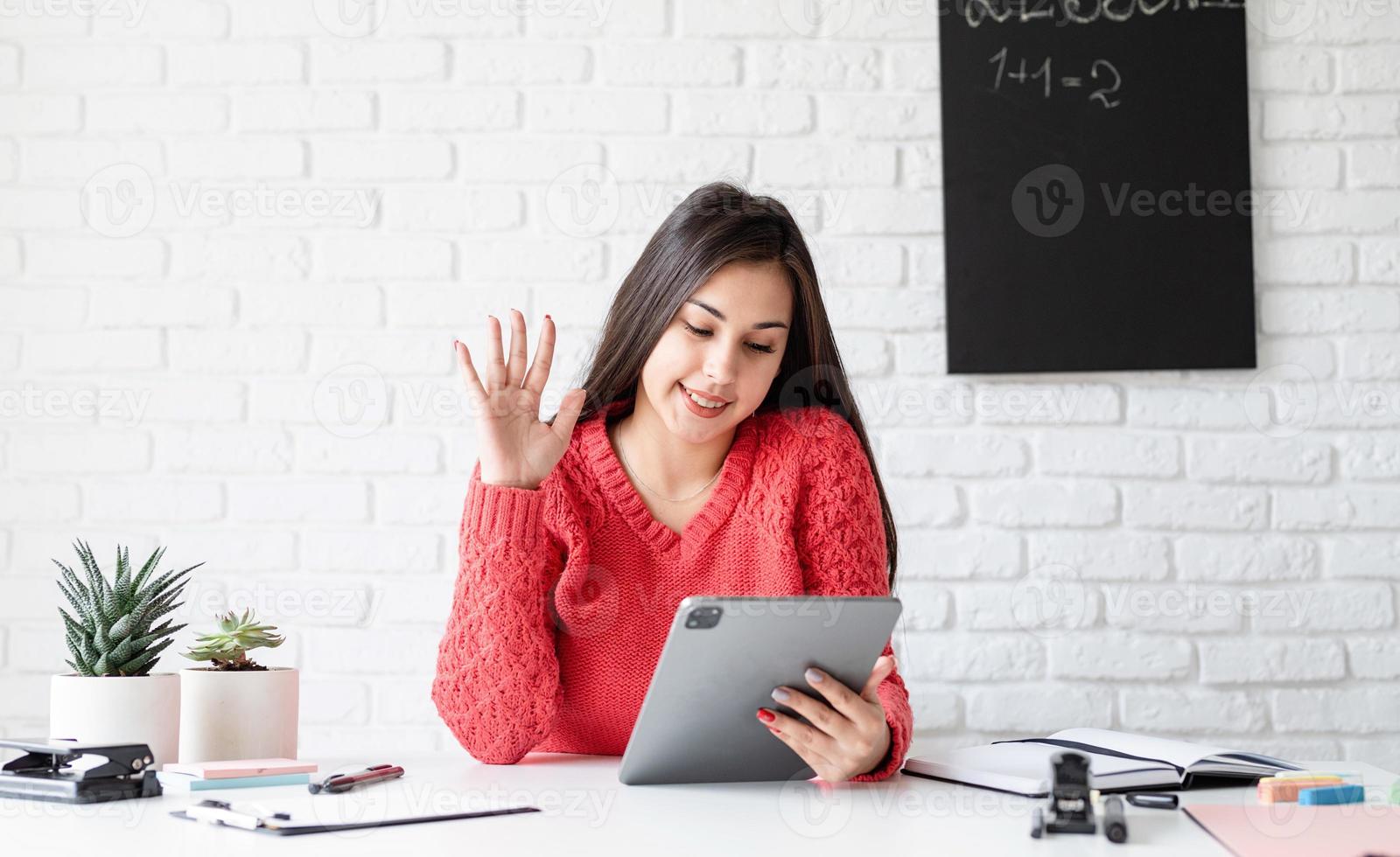 Mujer joven en auriculares negros enseñando inglés en línea mediante tableta foto