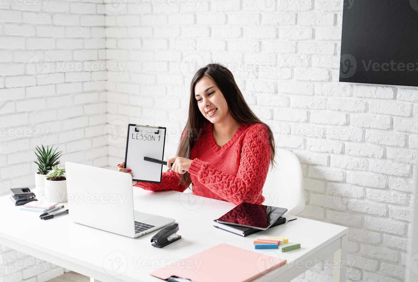 Young latin woman in red sweater teaching english online photo