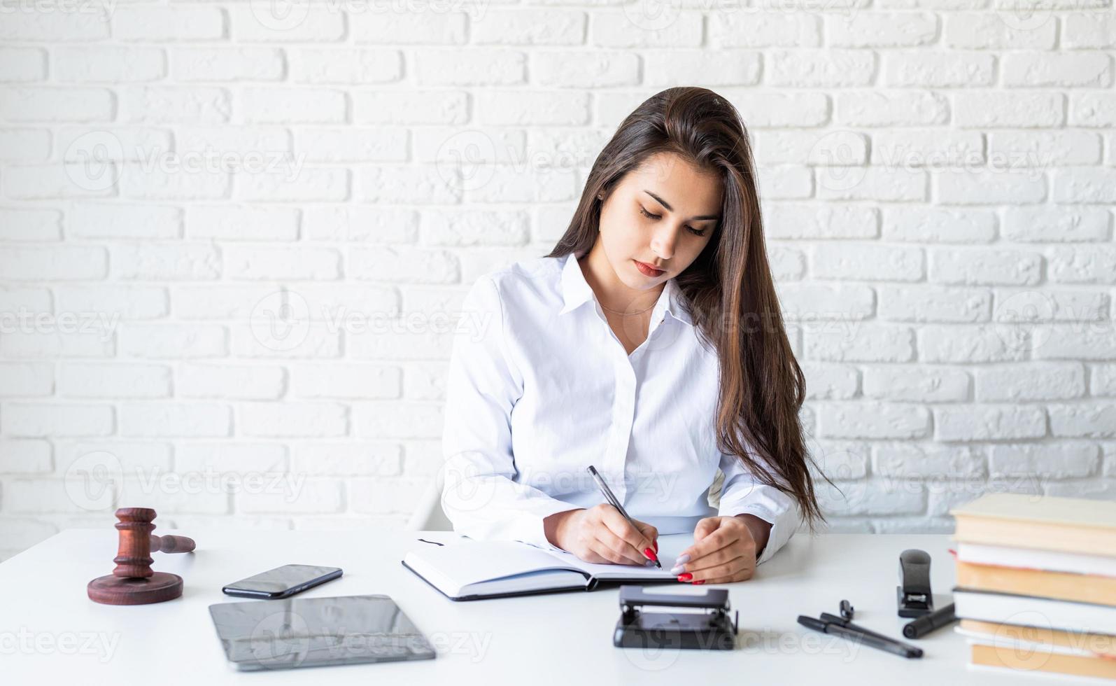 Joven abogada trabajando tomando notas en el cuaderno foto