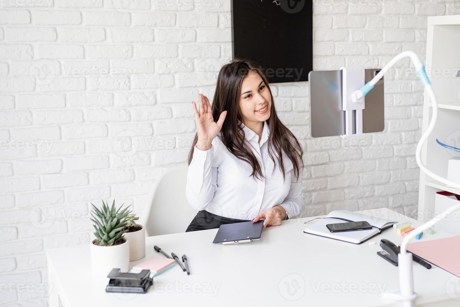 Young latin woman in white shirt teaching english online photo