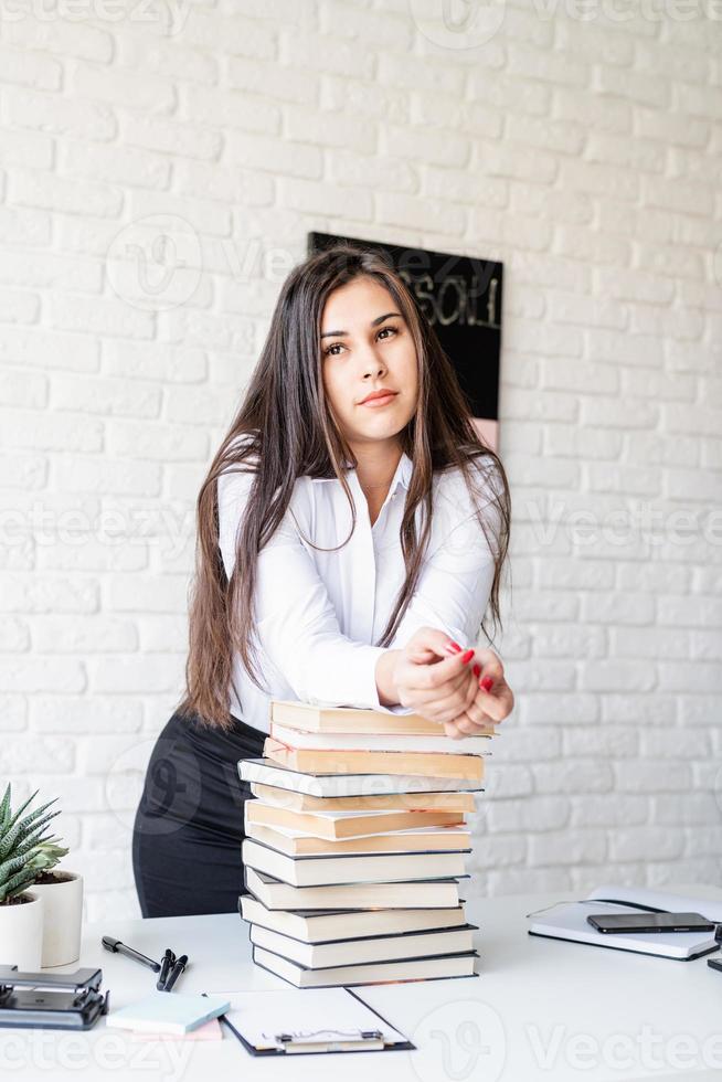 Profesor de pie con pila de libros mirando a otro lado listo para la lección foto