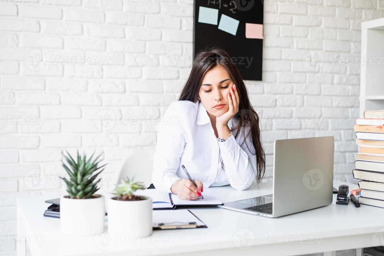 Young sad brunette teacher writing having online class photo