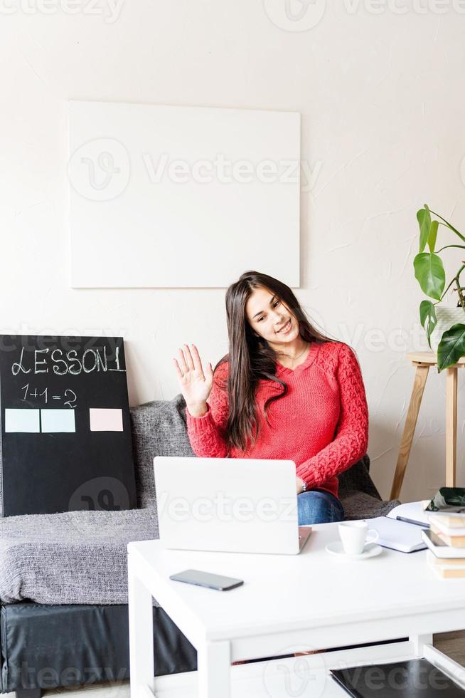 woman teaching english online using laptop sitting on the couch photo