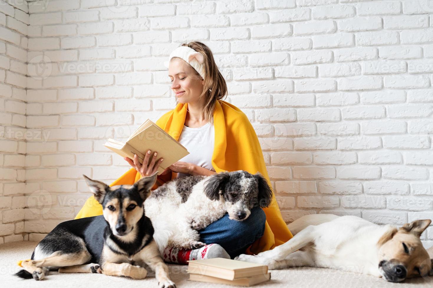 Funny young woman in yellow plaid sitting with her dogs reading a book photo