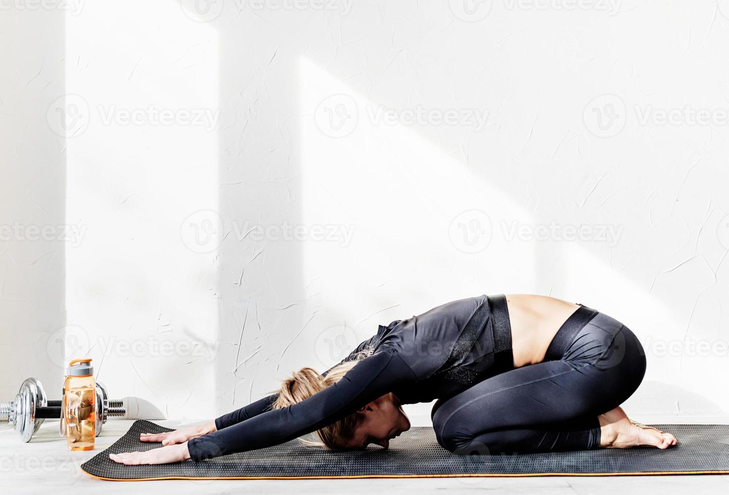 Joven atlética trabajando o haciendo estiramientos de yoga en casa foto