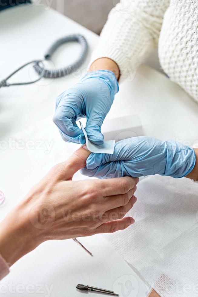 Manicure master cleaning nails making manicure to a client photo