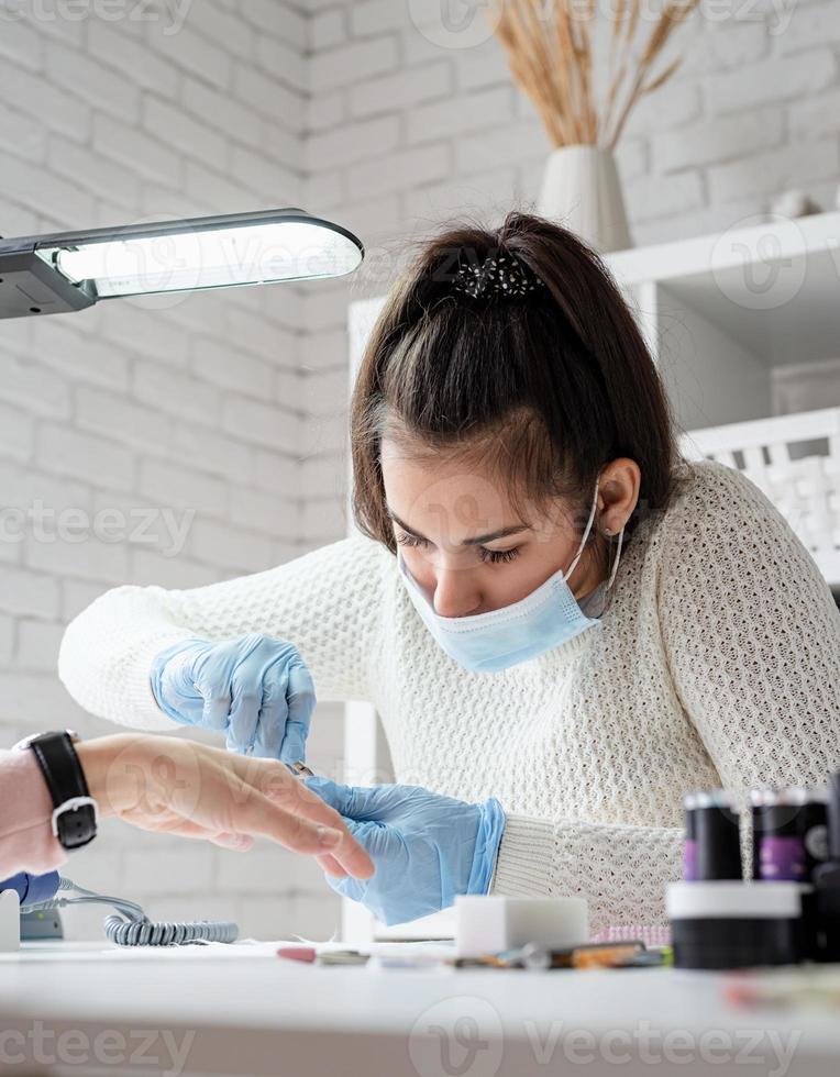 Manicure master using nippers to make manicure to a client photo