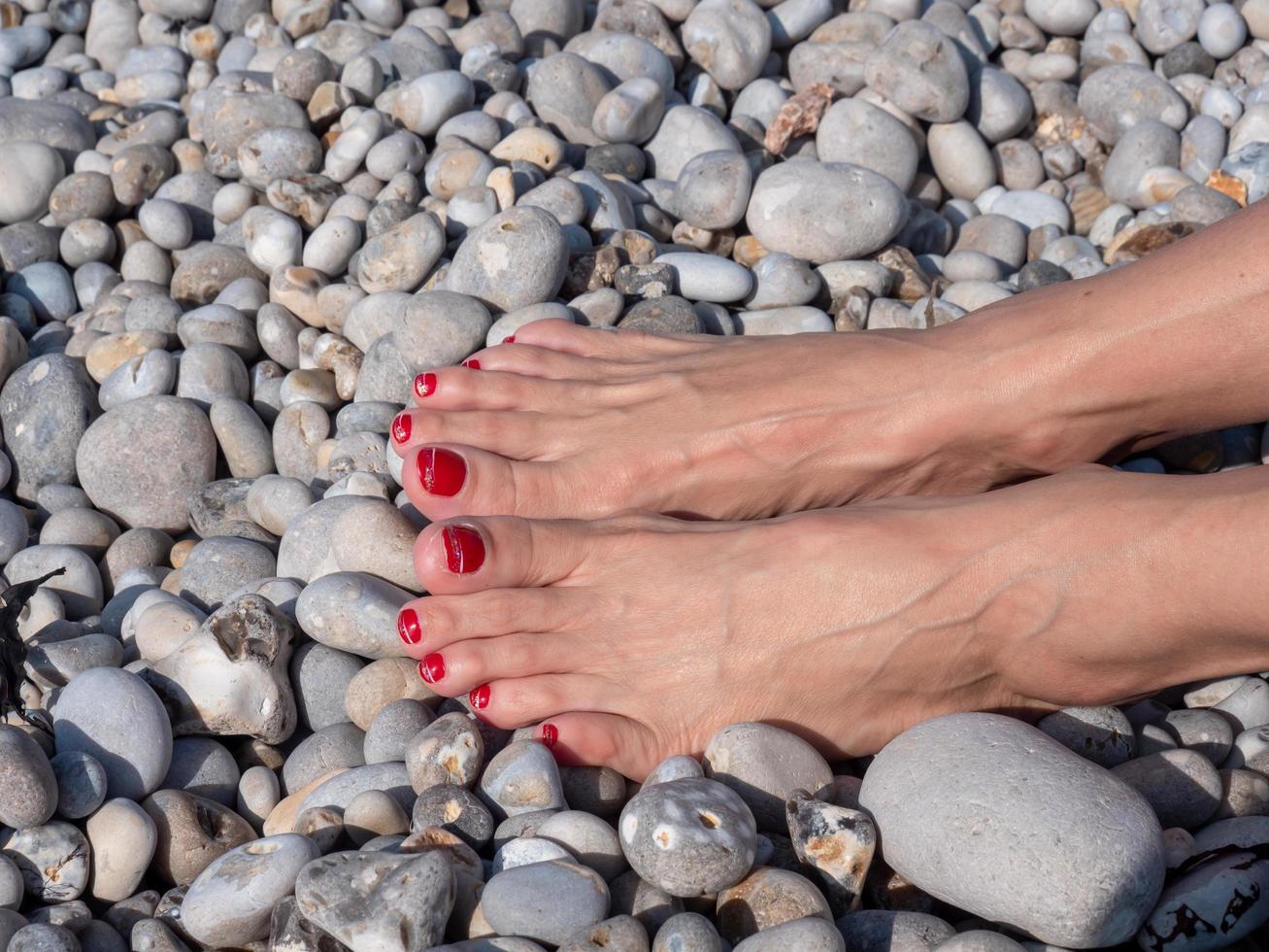 Pies femeninos en el fondo de la playa de guijarros, relajación de verano foto